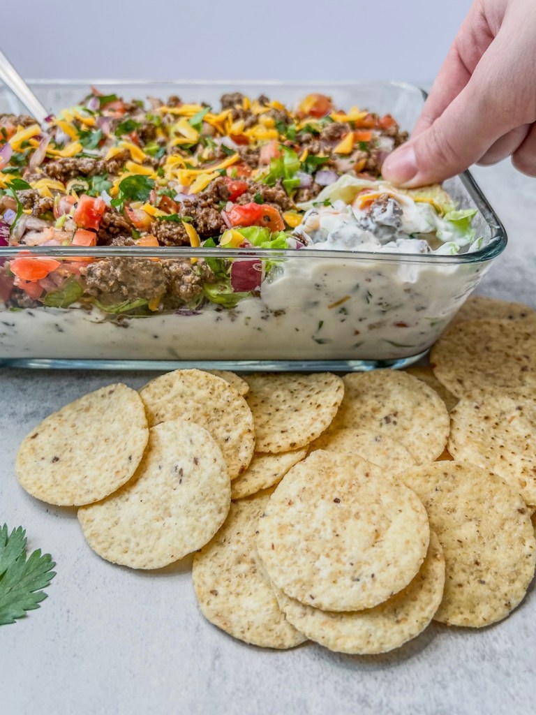 Beefy taco dip made with cottage cheese, Greek yogurt, sour cream, beef, spices, and fresh veggies, served with tortilla chips