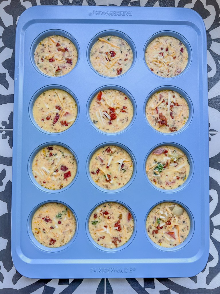 Broccoli cheddar bacon egg cups in a muffin pan before going into the oven