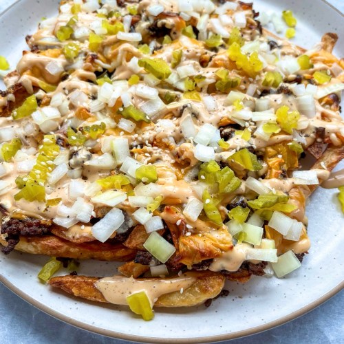 Cheesy smashburger fries with a Big Mac-style sauce drizzled on top, and some chopped pickle and onion