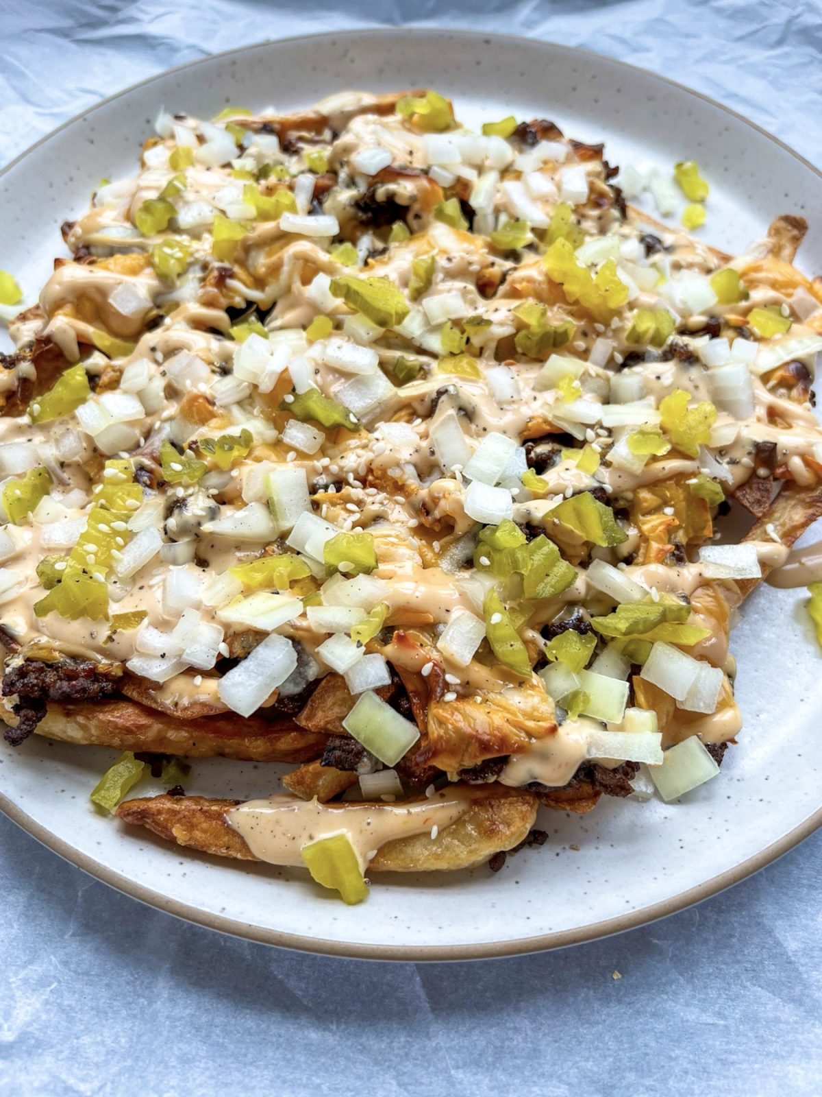 Cheesy smashburger fries with a Big Mac-style sauce drizzled on top, and some chopped pickle and onion