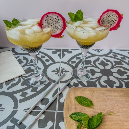Dragon fruit rum cooler cocktails in some specialty glasses with mint and dragon fruit slices for garnish