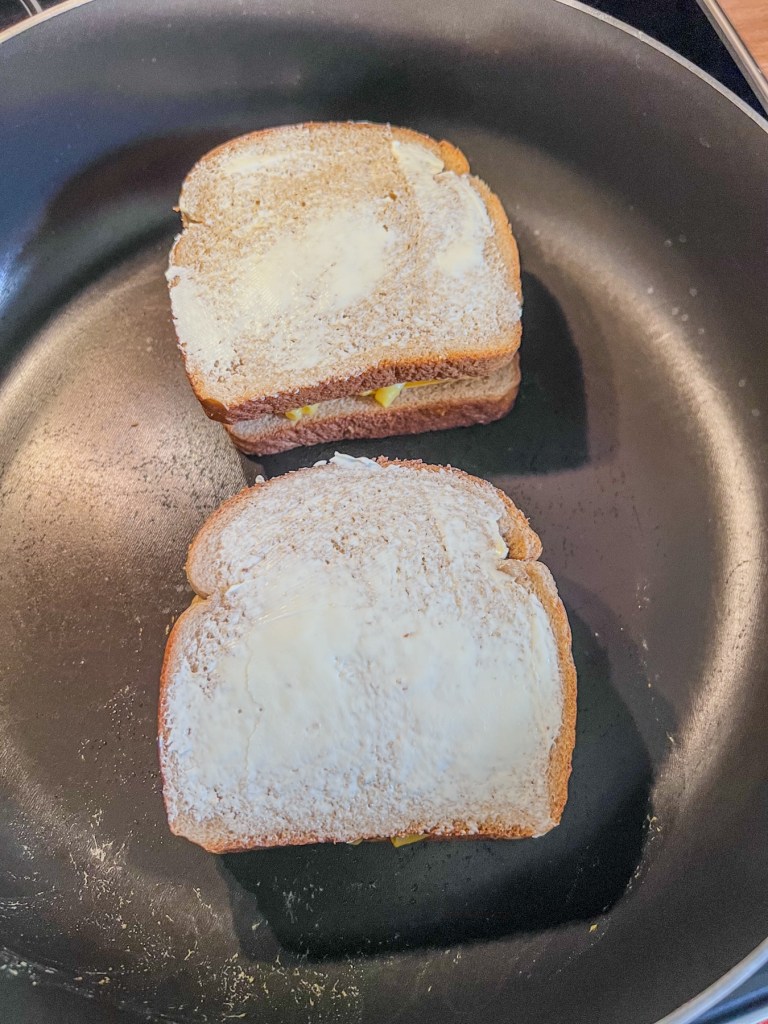 Grilled cheeses frying in a skillet