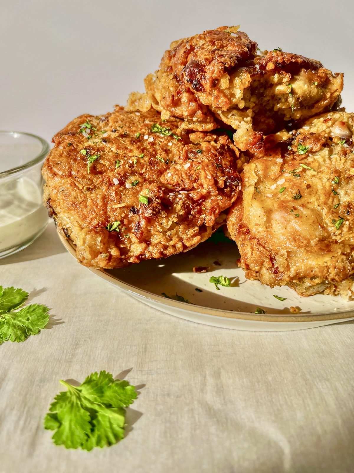 Hot honey fried chicken thighs with red pepper flakes, flaky salt, and minced cilantro on top with some dipping sauce on the side