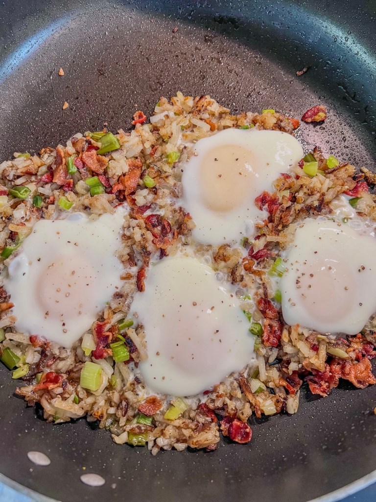 Bacon breakfast skillet cooking with some eggs that have just cooked until set