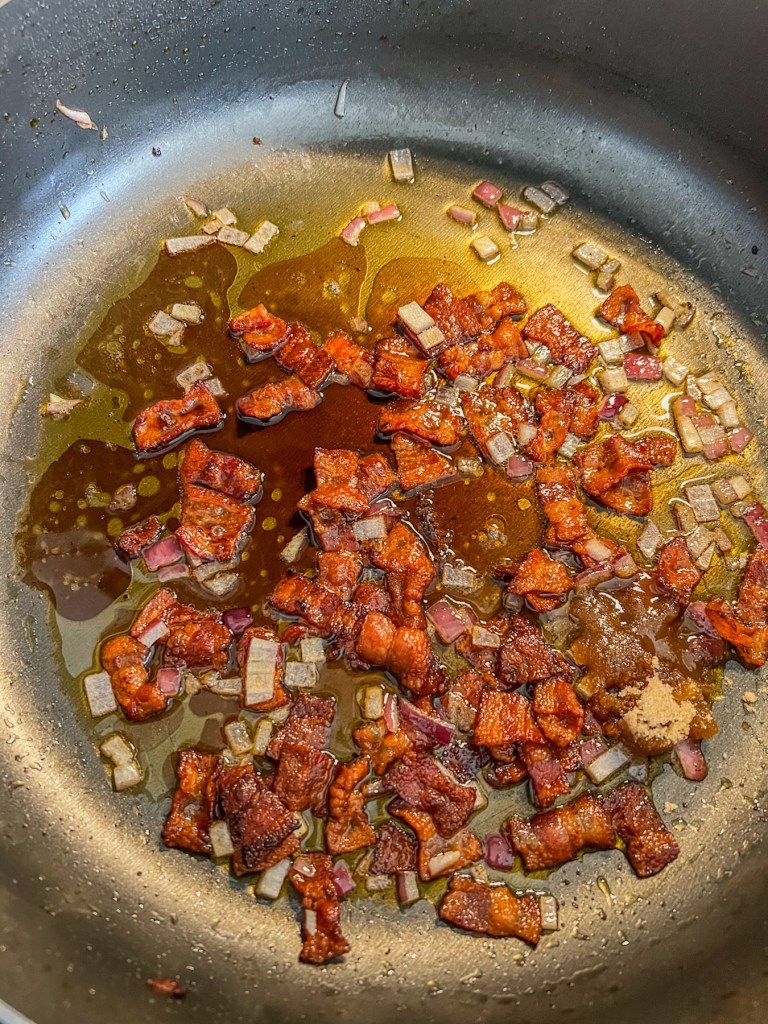 Bacon, red onion, balsamic vinegar, and brown sugar cooking in a skillet on the stove