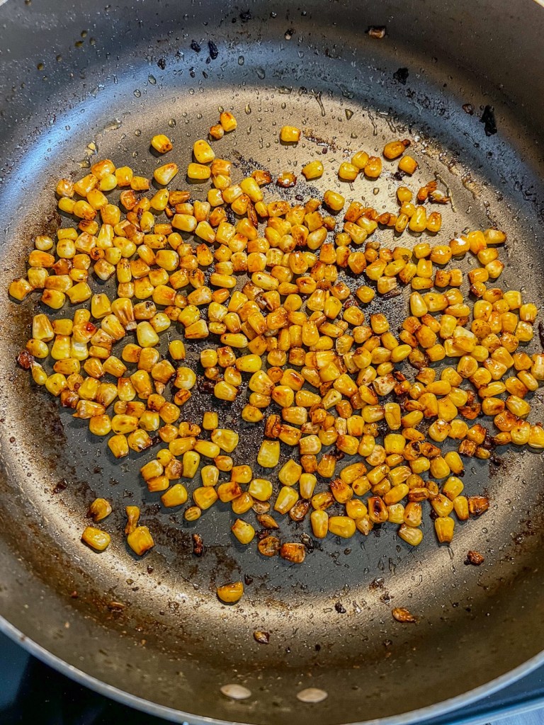Frozen corn that's been toasted and charred in some oil in a skillet