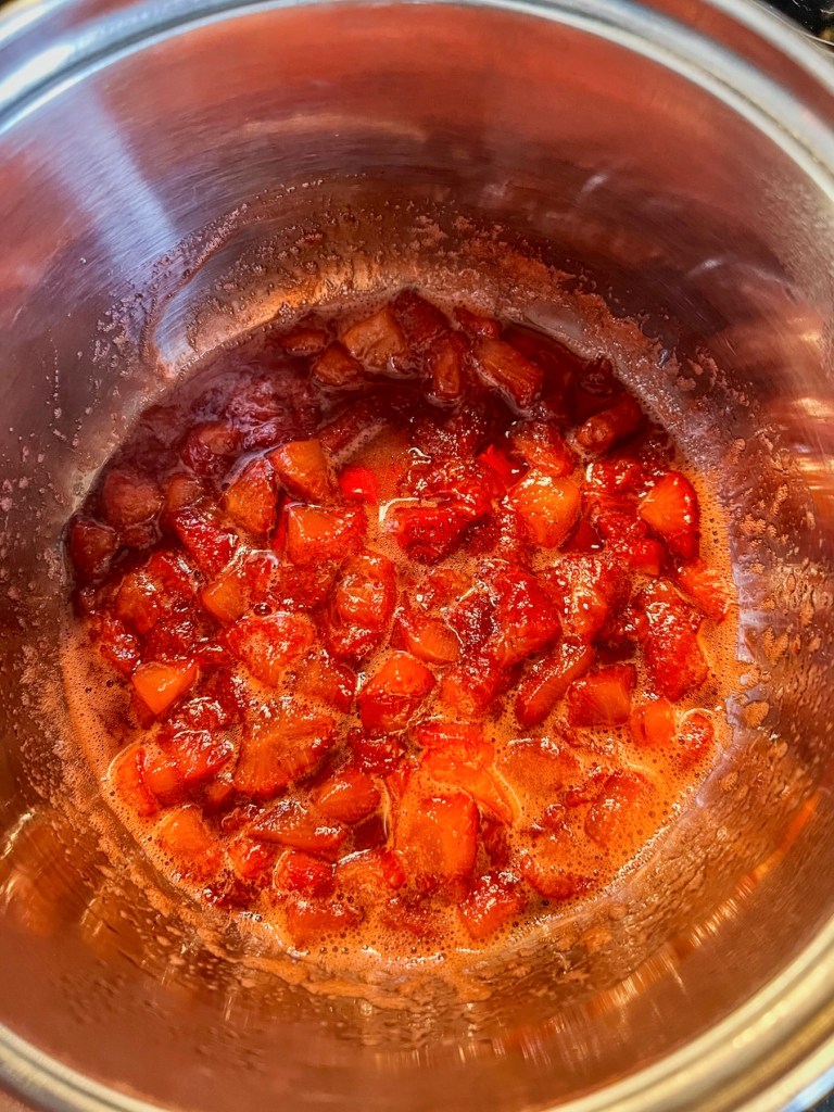 Strawberry jam cooking in a saucepan on the stove