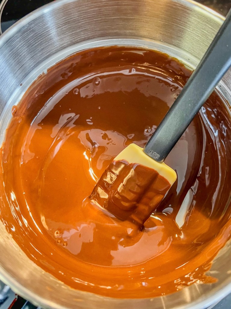 A mixture of melted semi-sweet chocolate chips and coconut oil in a saucepan