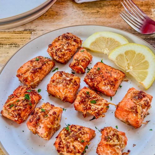 Crispy air fryer salmon bites fresh out of the air fryer, served with lemon wedges on the side
