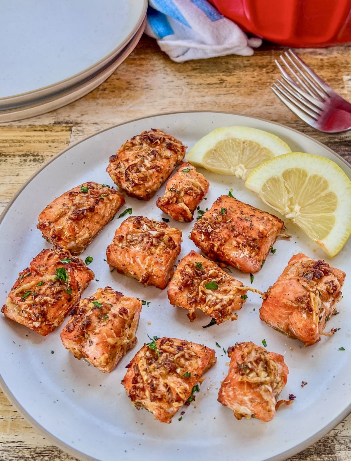 Crispy air fryer salmon bites on a plate with a side of lemon wedges and garden salad