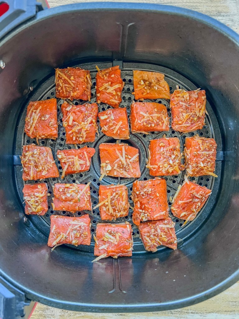 Salmon bites in an air fryer basket just before being air fried