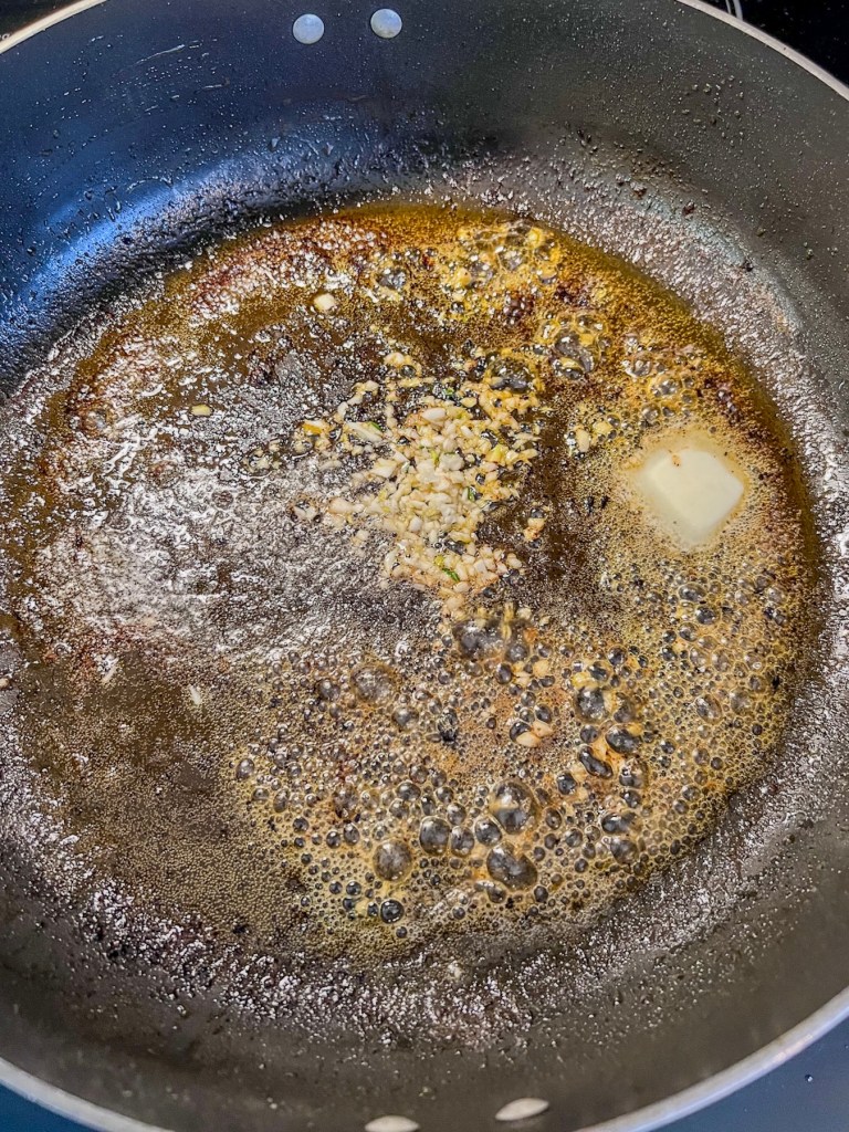 Garlic, butter, and broth cooking in a skillet