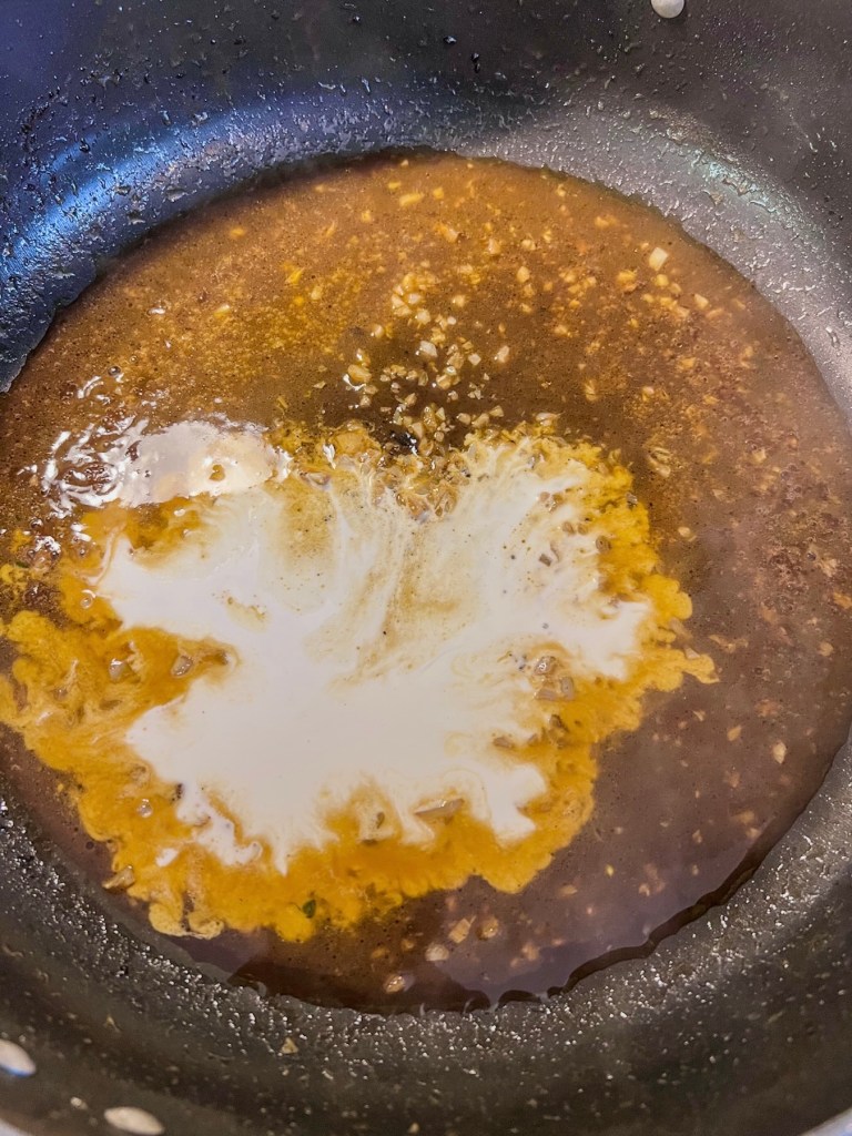 Garlic cream sauce being made in a skillet to spoon over pork chops