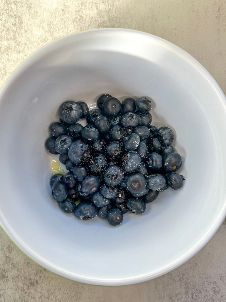 Blueberries, oil, and salt in a bowl before being roasted
