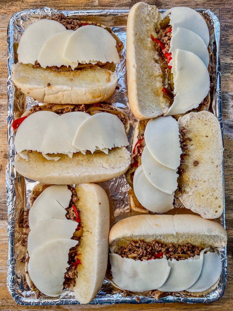 Hoagie buns with beef, provolone, and bell pepper just before getting broiled