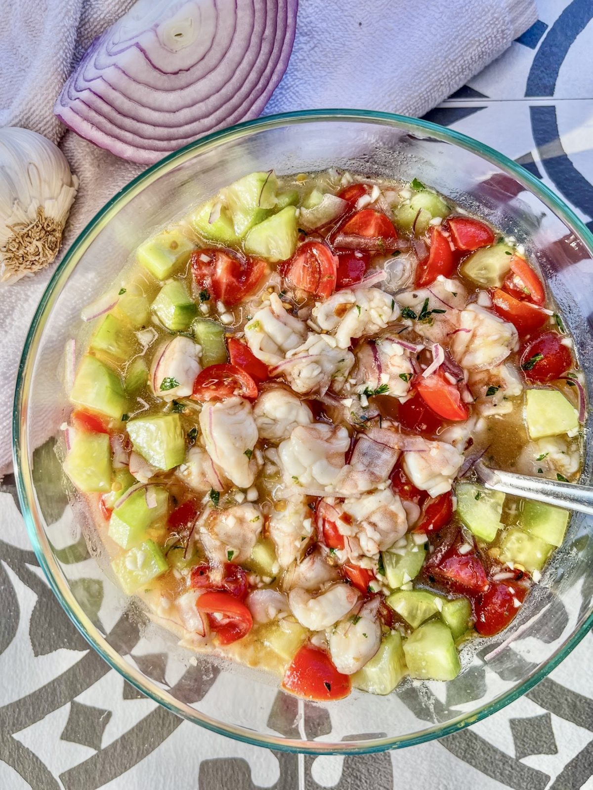 Cucumber shrimp ceviche in a bowl with some garlic and red onion off to the side