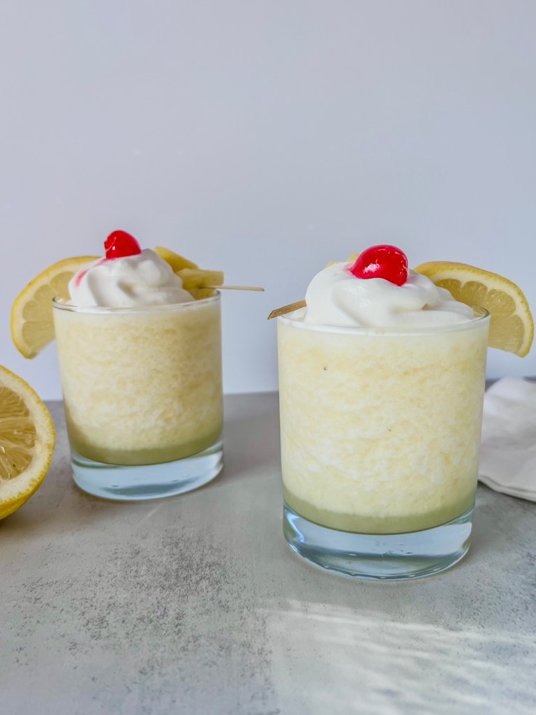 Two summery frozen pineapple creamsicle colada cocktails freshly made and served with garnishes