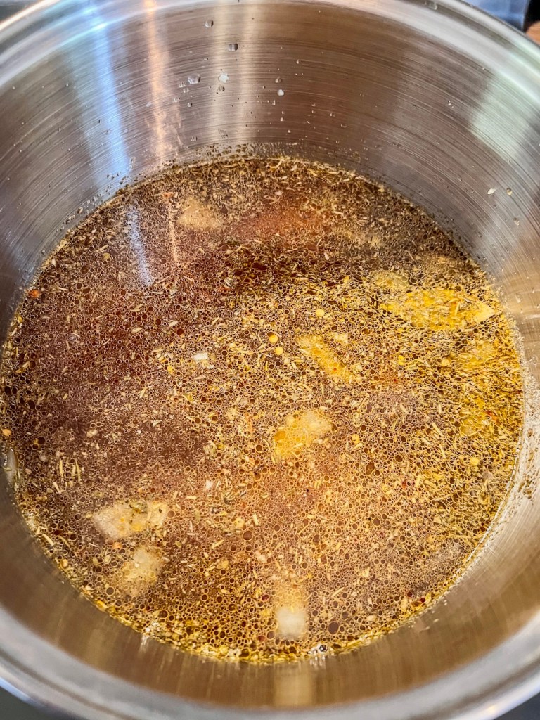 A large pot filled with veggies, spices, broth, and chicken breasts.