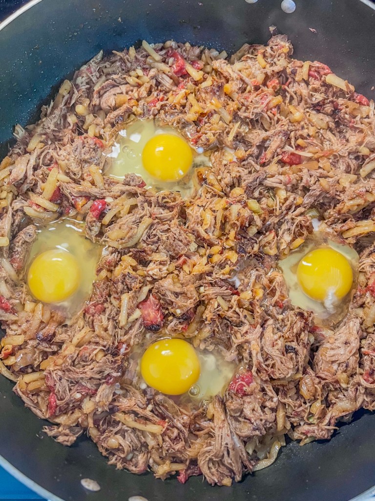 A breakfast skillet with some eggs just cracked into wells