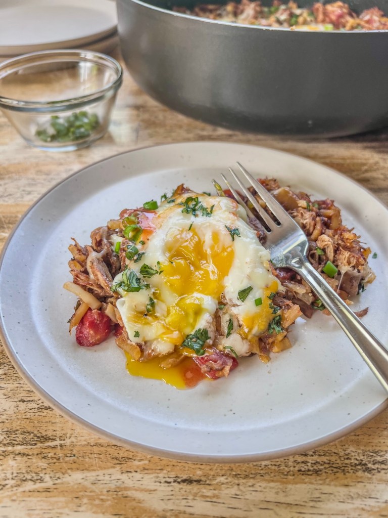 Pulled pork breakfast skillet on a plate with some fresh cilantro and green onion for garnish