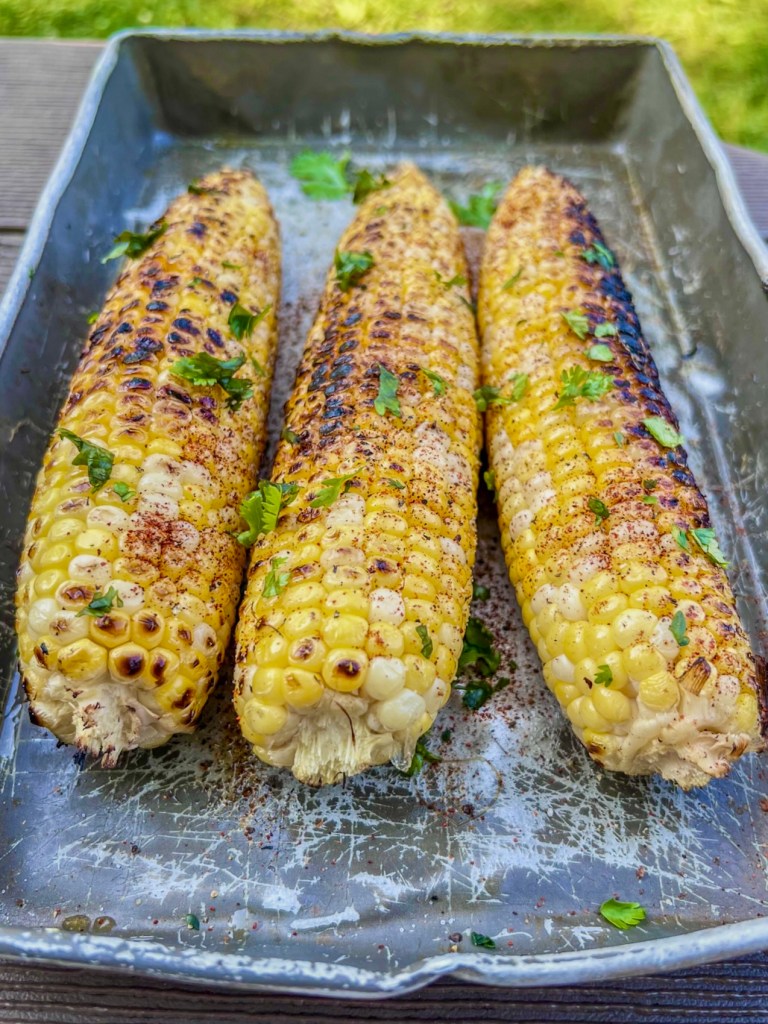 Freshly grilled corn with butter, herbs, and spices.