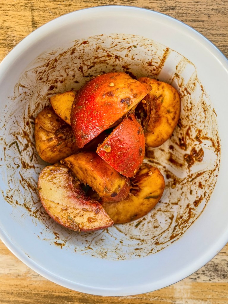 Peaches sliced into quarters and tossed with spices in a mixing bowl