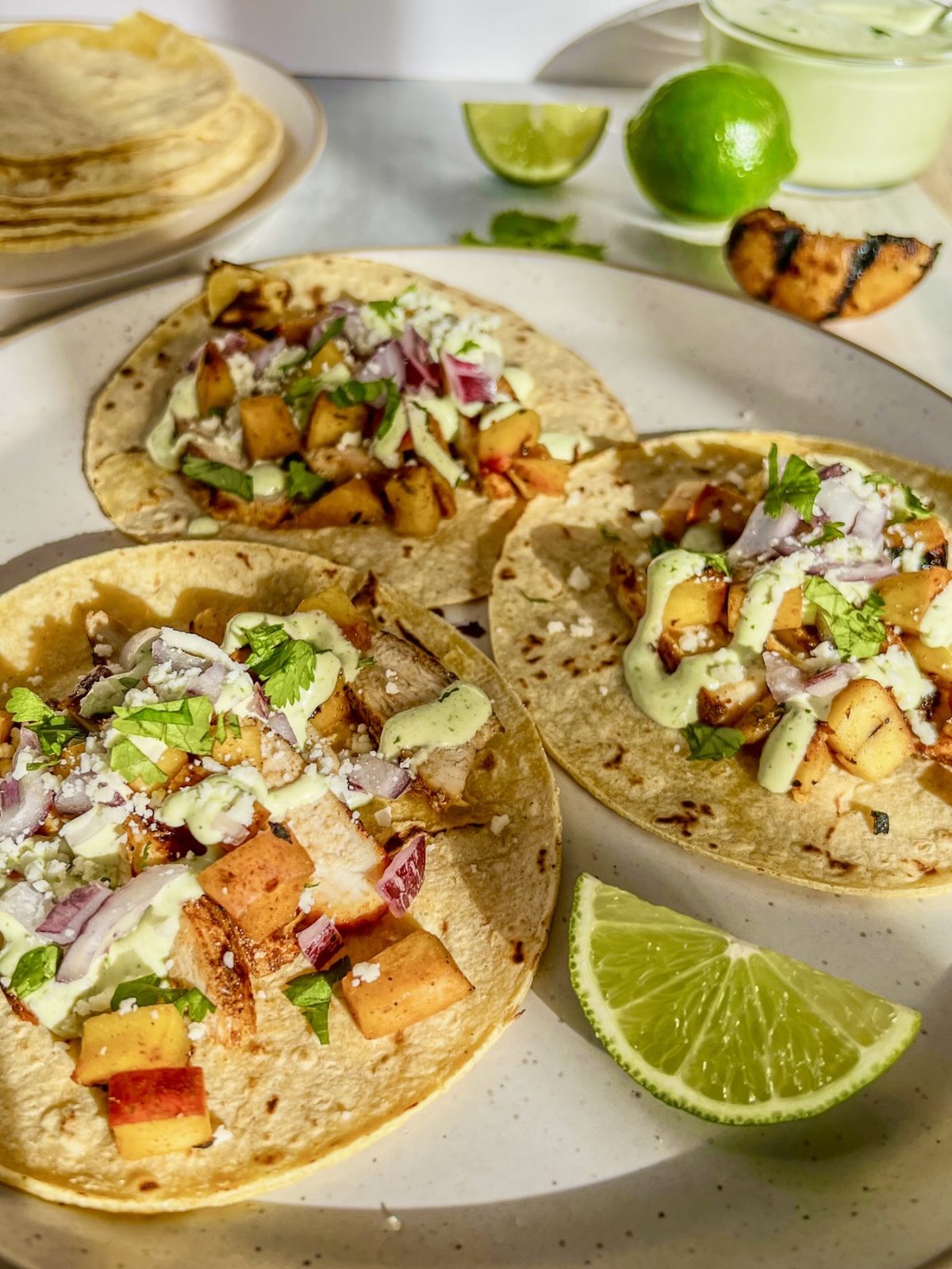 Grilled chicken street tacos with chili peaches served with cilantro, onion, cotija, and crema.