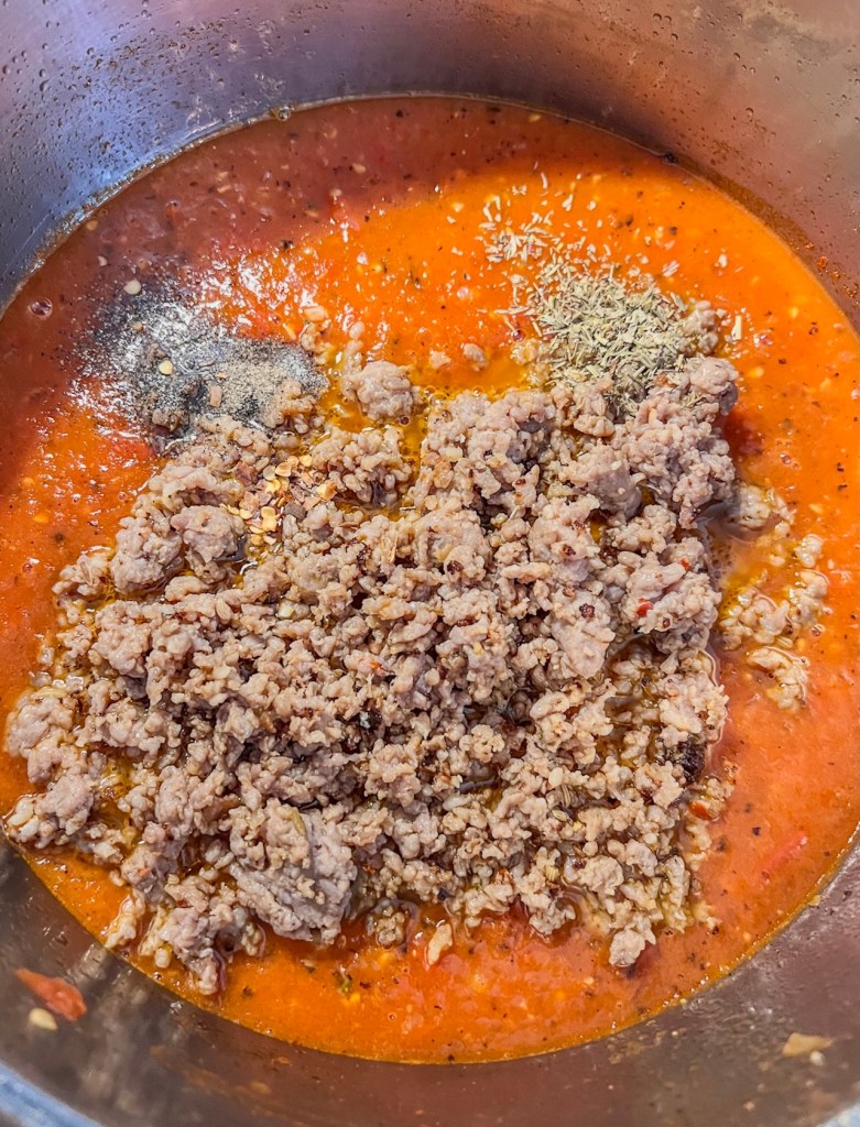 Tomato basil soup with Italian sausage cooking in a stockpot on the stove