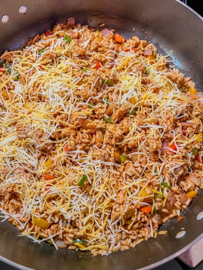 Filling for air fryer stuffed bell peppers in a skillet with melted cheese on top.