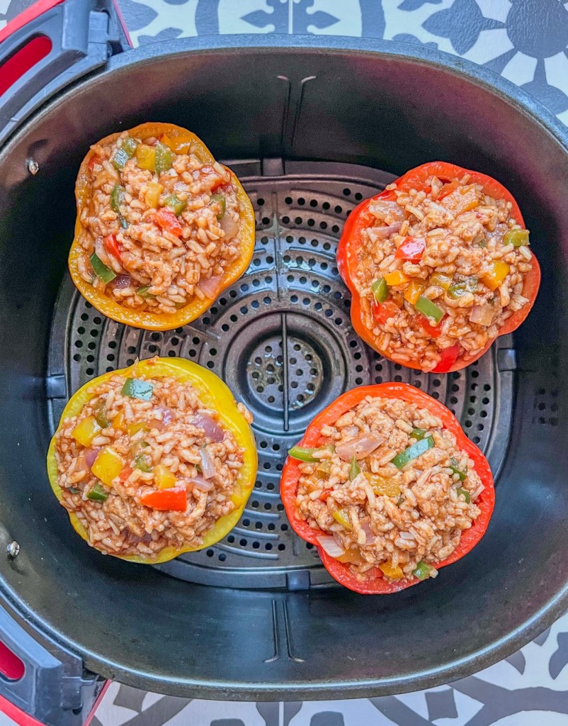 Stuffed bell peppers in an air fryer basket just before getting air fried