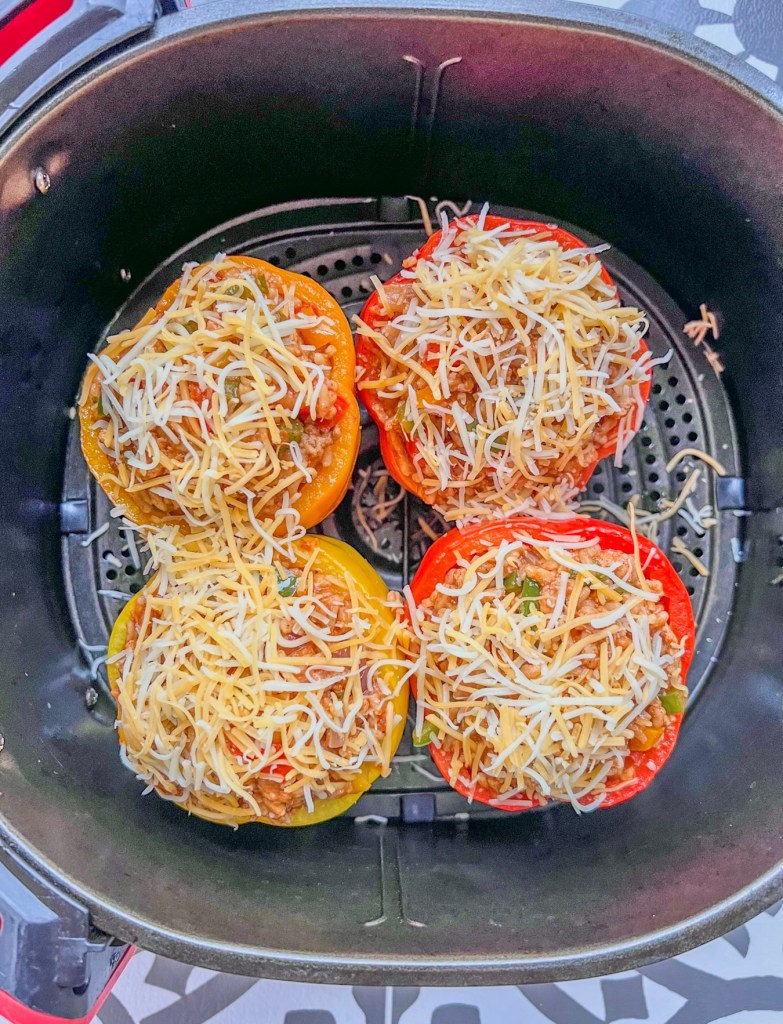 Stuffed bell peppers with cheese on top in an air fryer basket