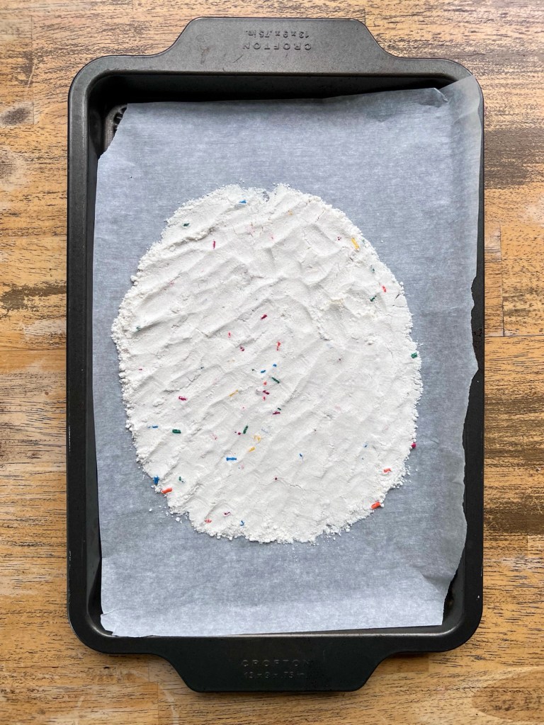 Funfetti cake mix spread out onto a baking sheet to be heat-treated