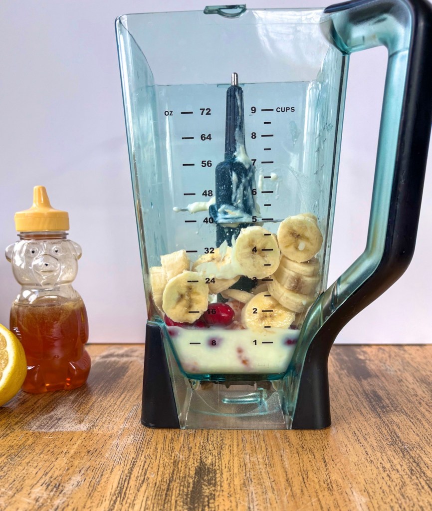 Banana, frozen cranberries, frozen clementines, Greek yogurt, vanilla, honey, and fresh lemon juice in a blender to make a breakfast smoothie.