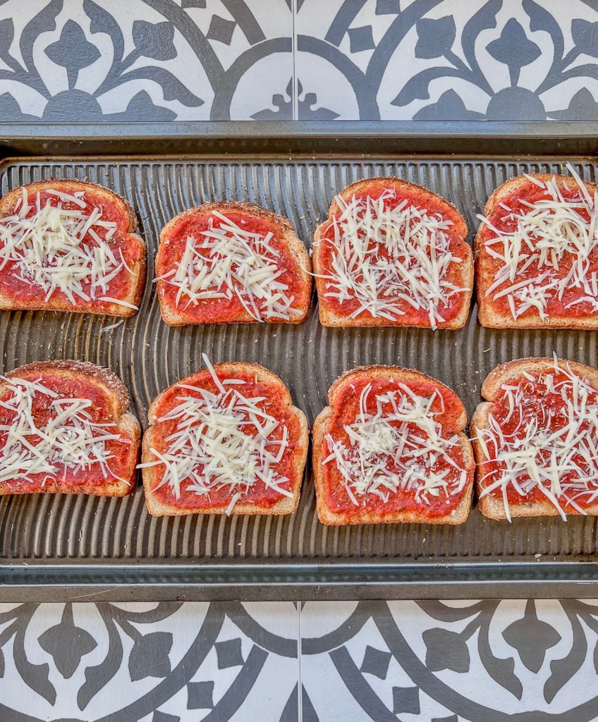 Bread that's been buttered and smeared with pizza sauce, then topped with parmesan cheese.
