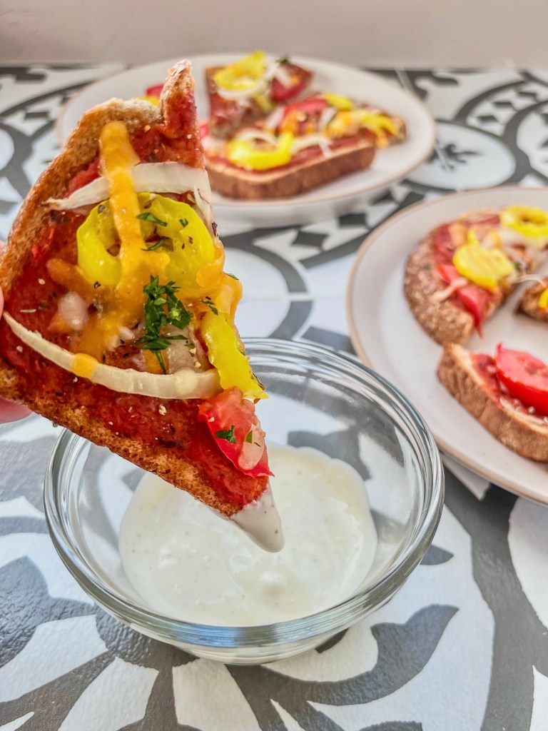 Garlic bread pizzas served with ranch dressing on the side.