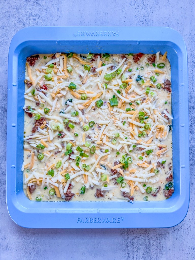 An egg mixture in a blue baking pan just before going into the oven.