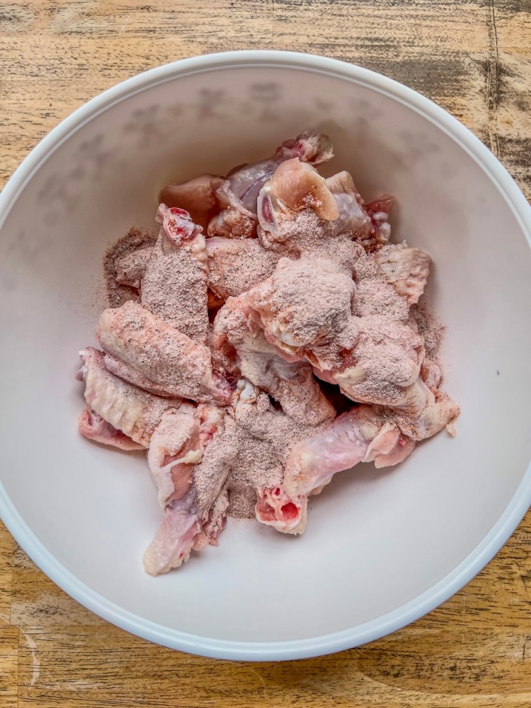 Chicken wings in a mixing bowl with spices and oil