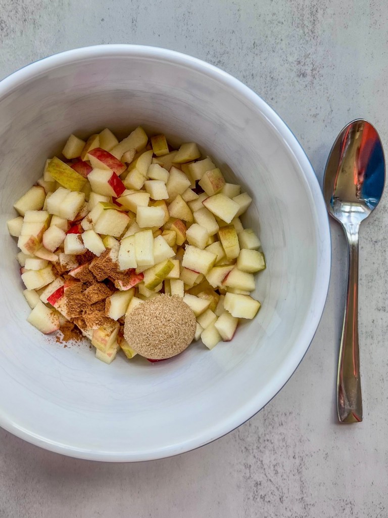 Diced apples in a bowl with brown sugar, cinnamon, and salt.