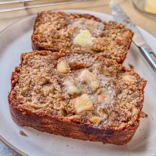 Apple banana bread freshly sliced and smeared with butter.