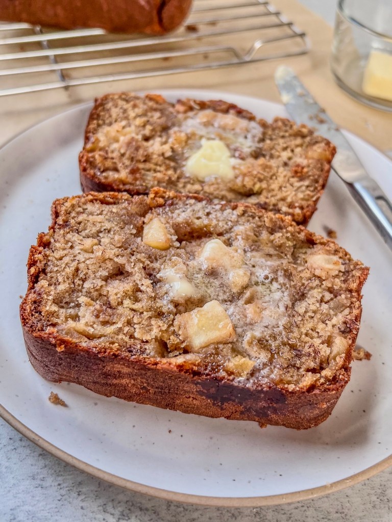 Apple banana bread freshly sliced and smeared with butter.