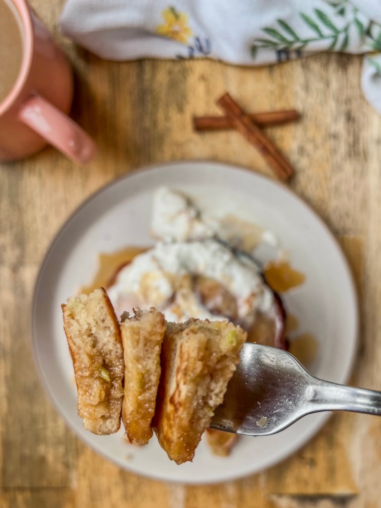 Caramel apple pancakes served hot with caramel, whipped cream, and cinnamon.