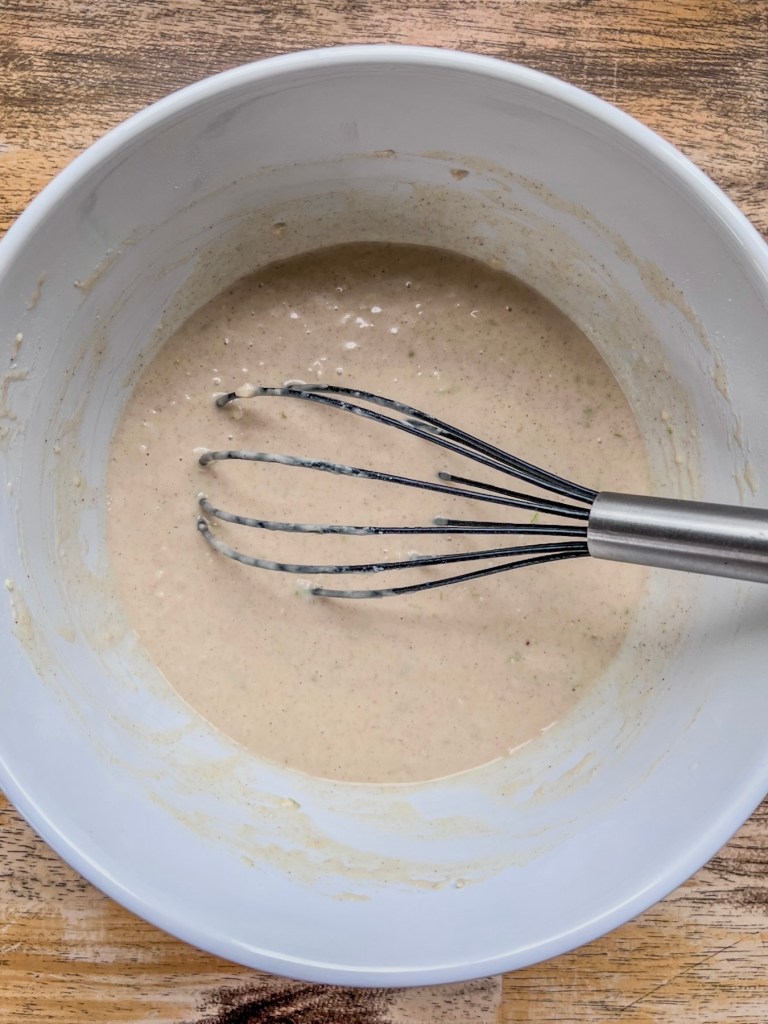 Caramel apple pancake batter in a large bowl with a whisk inside.