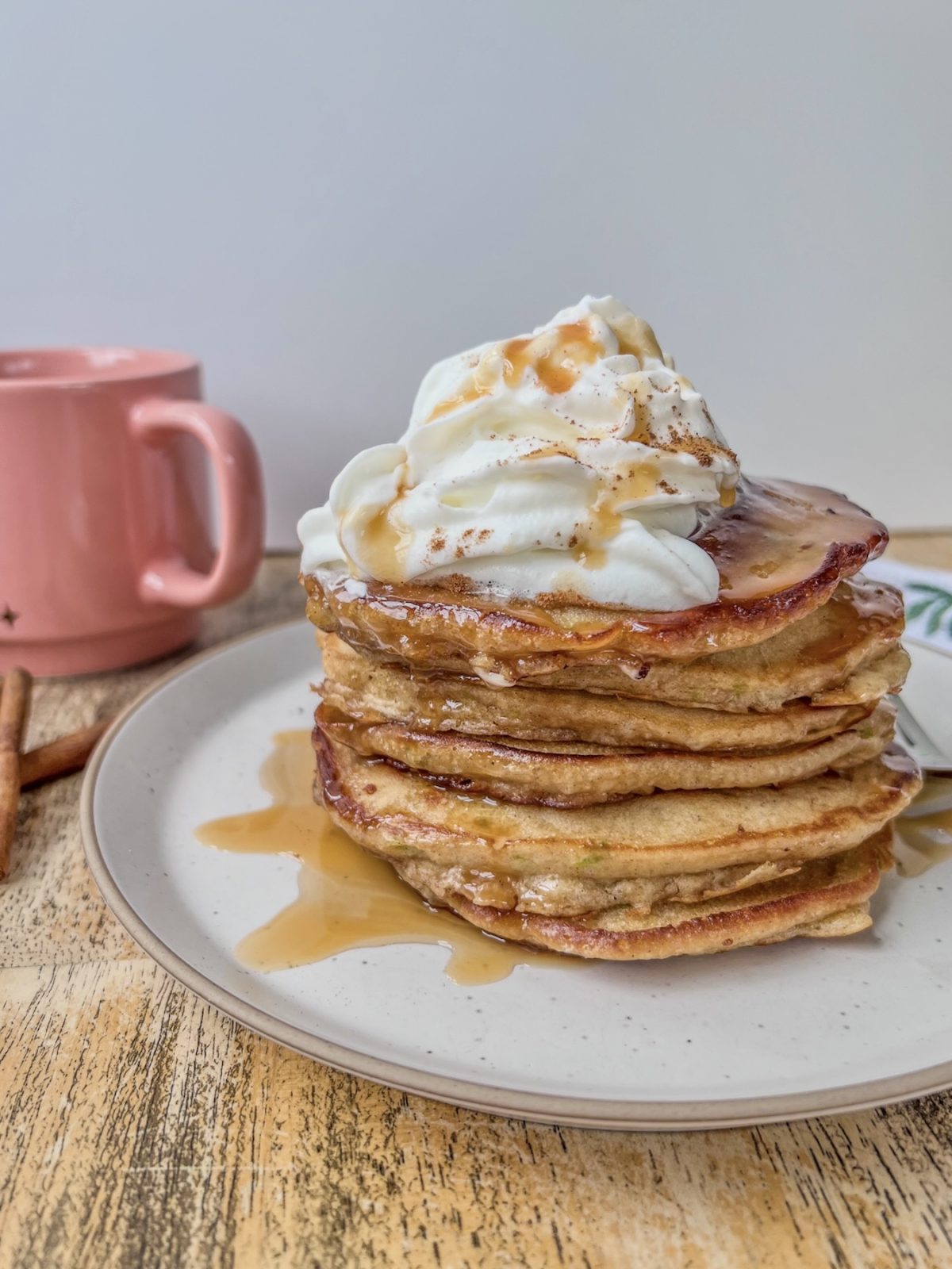 Caramel apple pancakes with whipped cream, caramel drizzle, and cinnamon on top.