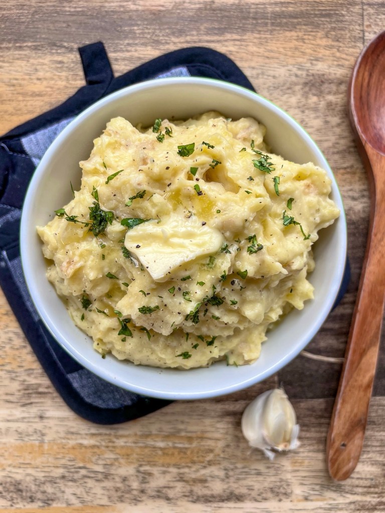 Creamy garlic mashed potatoes with fresh basil on top, served as a delicious dinner side.