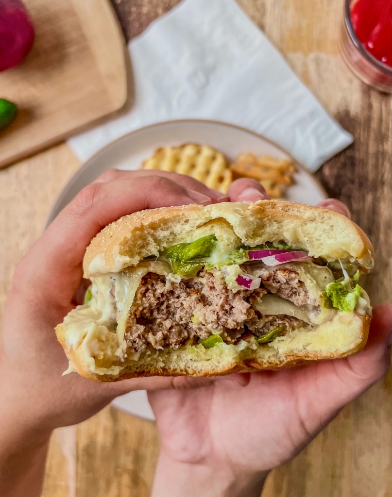 White cheddar and onion jalapeño burgers with some fries and sauce served on the side.