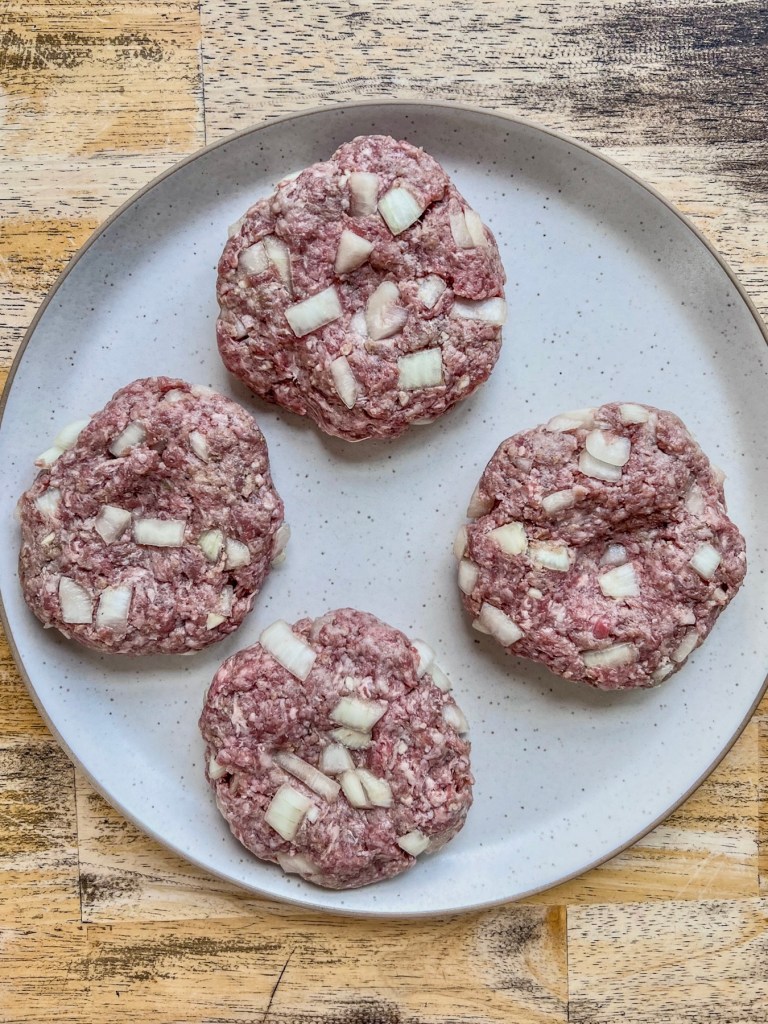 Raw burger patties on a plate just before going into the fridge.