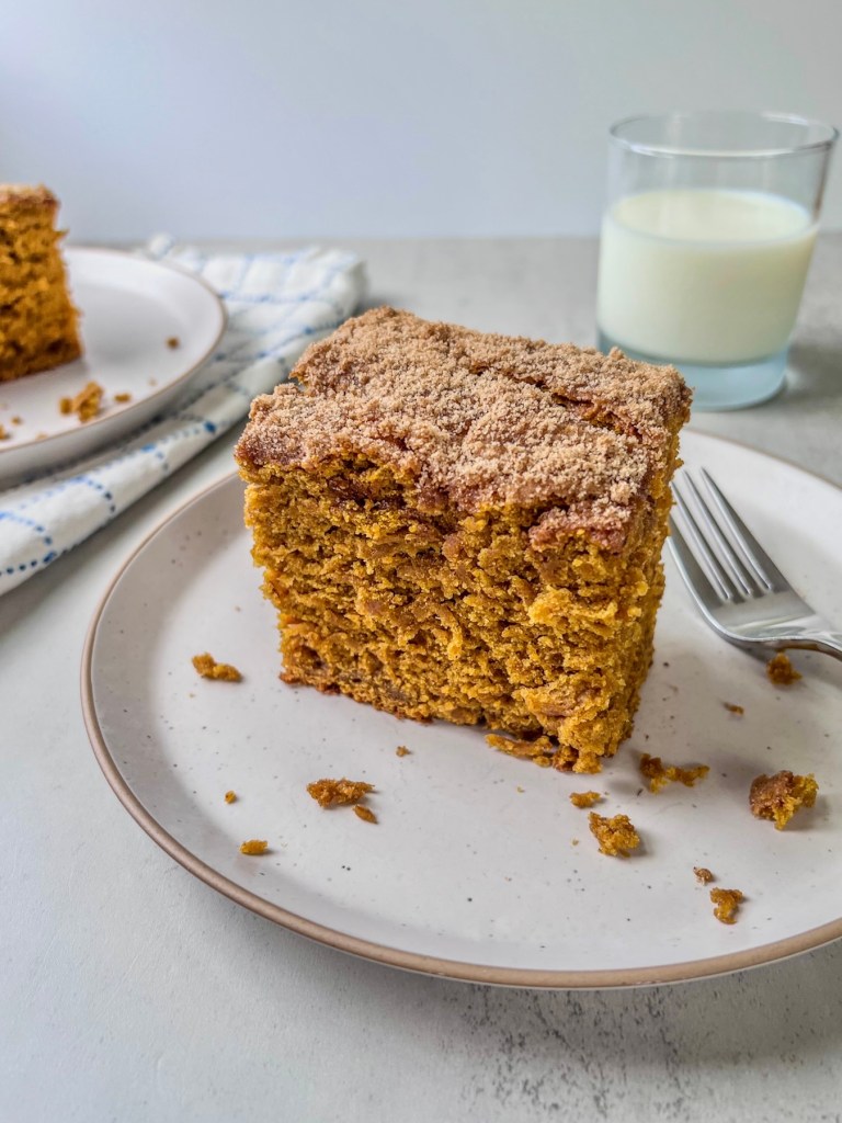 Brown butter pumpkin crumb cake on a plate with a glass of milk off to the side.