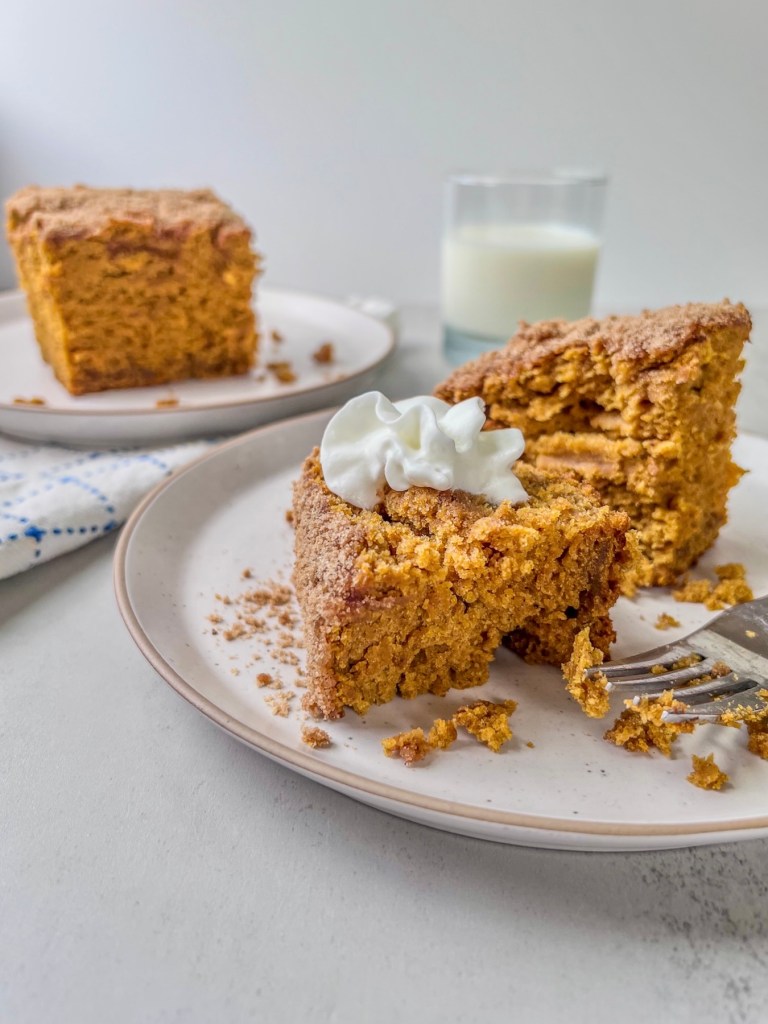 Brown butter pumpkin crumb cake served with whipped cream on top and a glass of milk