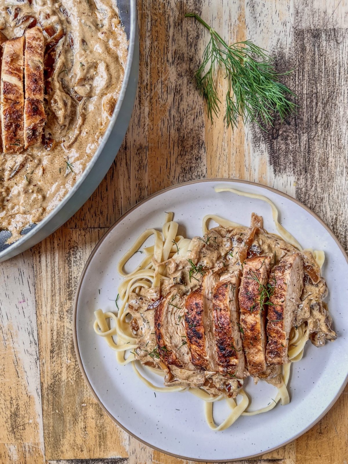 Caramelized onion chicken skillet served on a plate with some fresh dill sprinkled on top.