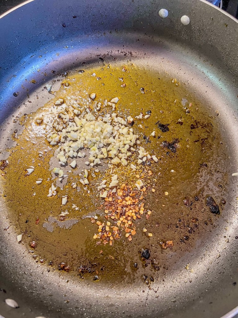 Garlic, oil, and spices cooking in a skillet